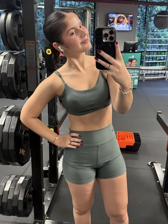 Cliente Zaia com top e short verde-acinzentado na academia