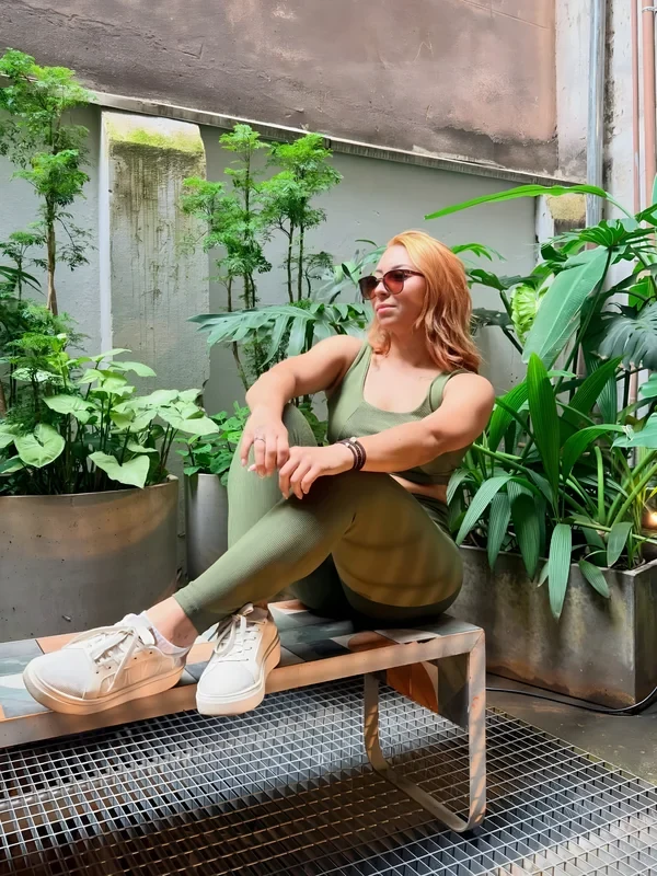 Cliente Zaia com conjunto verde-oliva sentada entre plantas